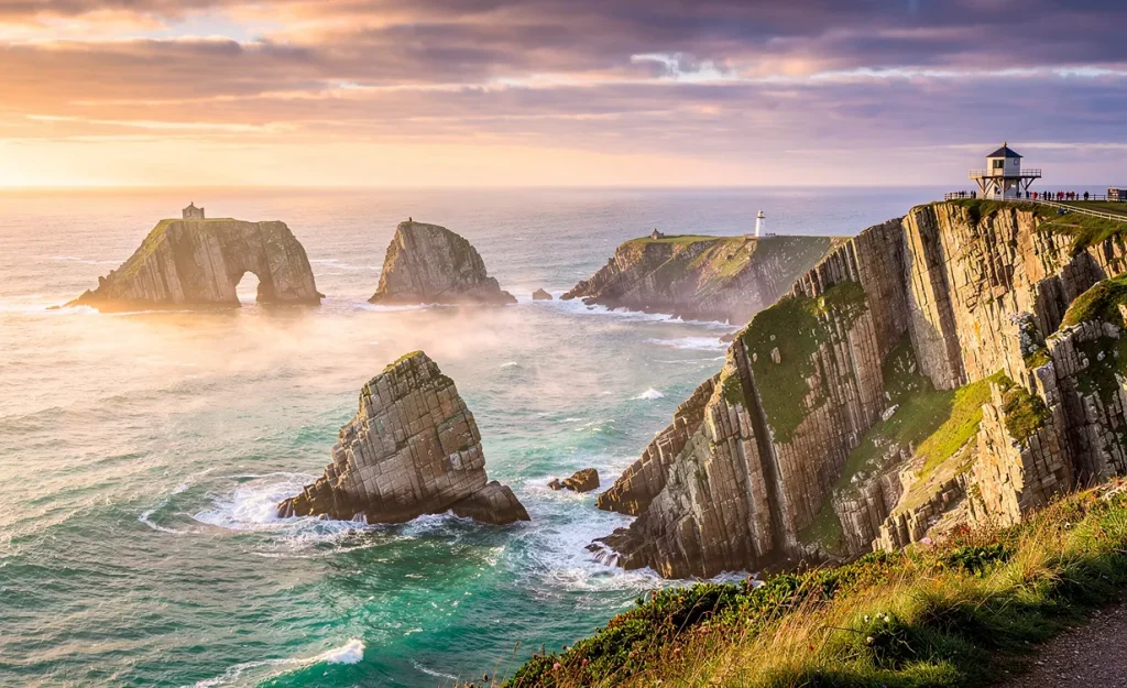Côte sauvage de la presqu'île de Crozon au coucher du soleil, avec falaises, eaux turquoise et six monuments éclairés par une lumière dorée.